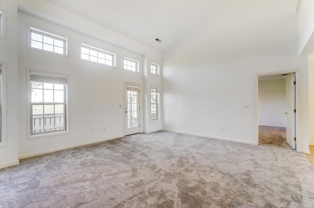 unfurnished room with light colored carpet and a towering ceiling