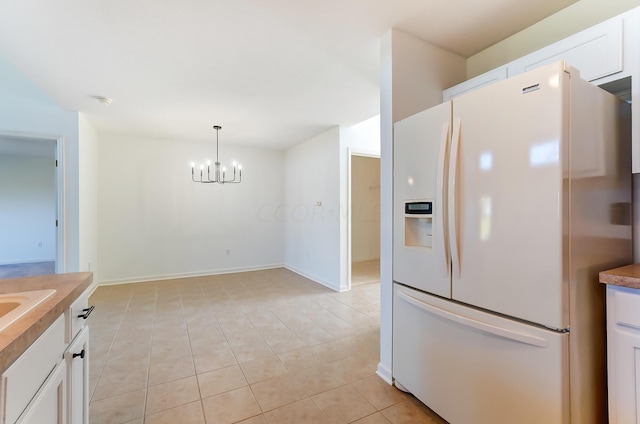 kitchen with pendant lighting, white cabinets, white refrigerator with ice dispenser, a notable chandelier, and light tile patterned floors