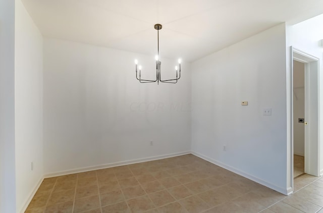 spare room with a notable chandelier and light tile patterned flooring