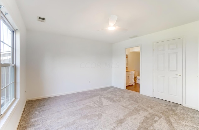 unfurnished bedroom with ceiling fan, ensuite bathroom, and carpet flooring