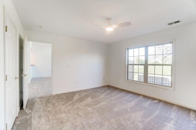 spare room with ceiling fan and light colored carpet