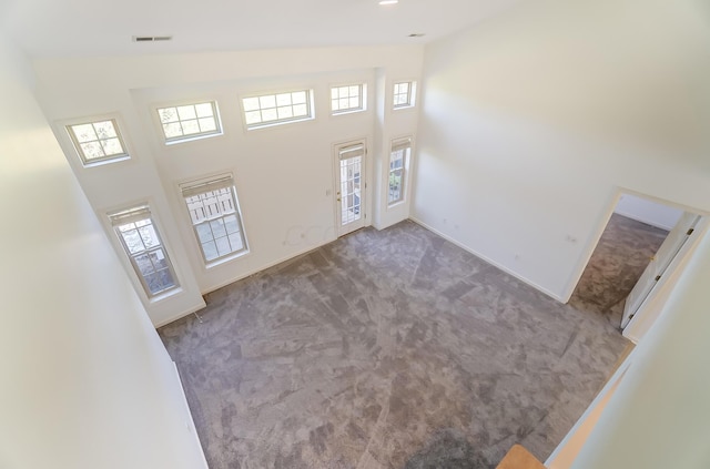 unfurnished living room with carpet floors and a towering ceiling