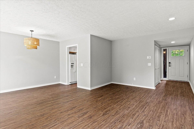 unfurnished living room with dark hardwood / wood-style flooring and a textured ceiling