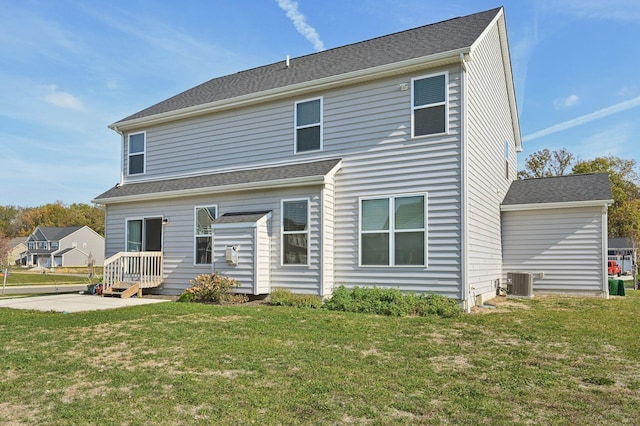 rear view of property featuring a yard, a shingled roof, and central AC