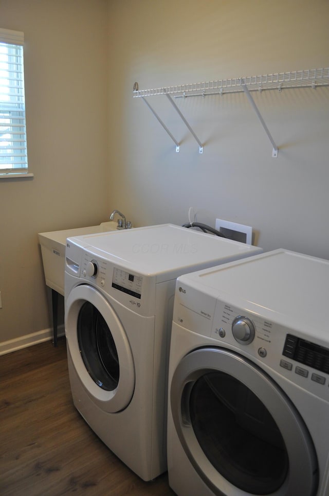 washroom featuring laundry area, washer and clothes dryer, dark wood finished floors, and baseboards