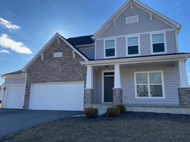 craftsman house featuring an attached garage, covered porch, stone siding, and aphalt driveway