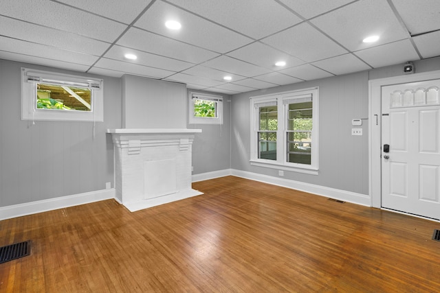 unfurnished living room with a paneled ceiling and wood-type flooring