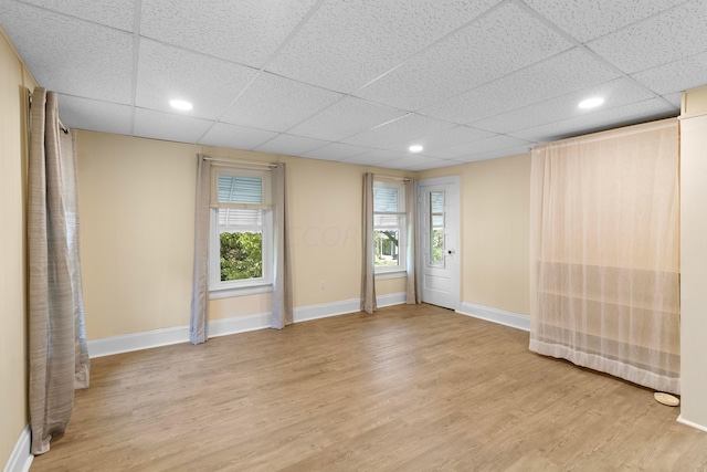 empty room featuring a drop ceiling and light hardwood / wood-style floors