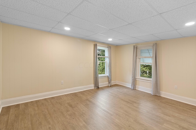 unfurnished room featuring light hardwood / wood-style floors and a drop ceiling