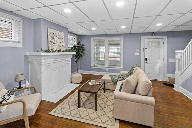 living area with recessed lighting, wood finished floors, baseboards, stairway, and a brick fireplace