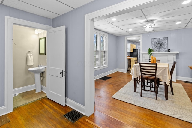 dining space featuring a paneled ceiling, a ceiling fan, visible vents, baseboards, and wood-type flooring