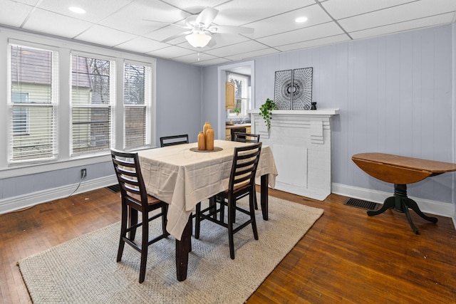 dining area featuring a paneled ceiling, wood-type flooring, ceiling fan, and baseboards