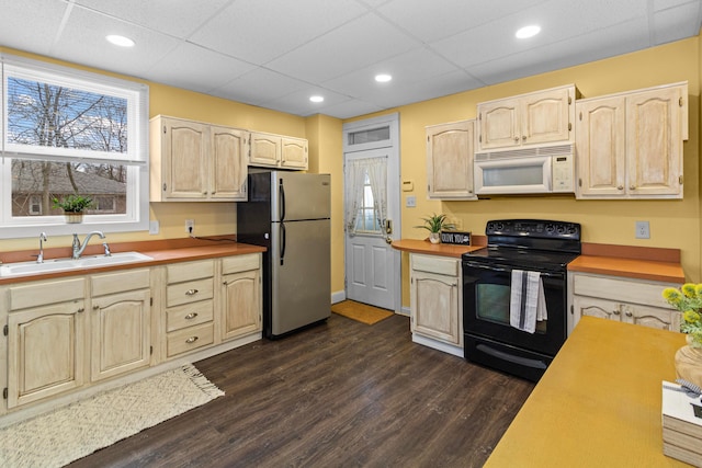 kitchen featuring white microwave, black range with electric cooktop, dark wood-type flooring, a sink, and freestanding refrigerator