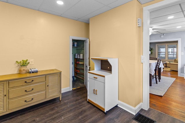 interior space with dark wood-type flooring, light countertops, visible vents, and baseboards