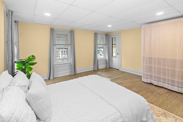 bedroom with a paneled ceiling, baseboards, and wood finished floors