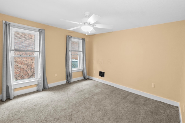 carpeted empty room featuring a ceiling fan, visible vents, and baseboards