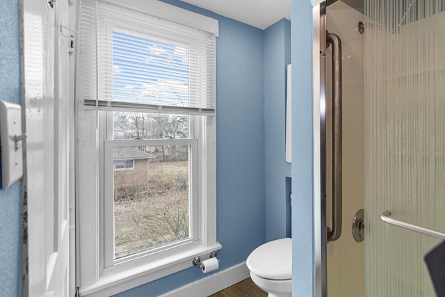 bathroom with walk in shower, toilet, and baseboards