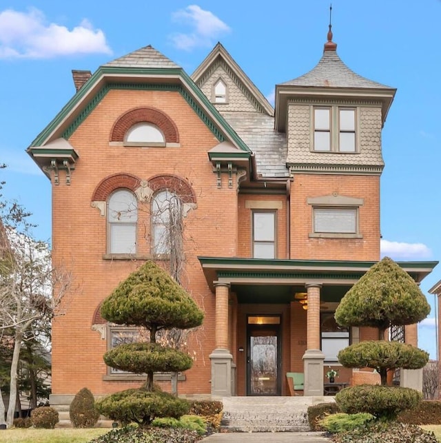 victorian house featuring brick siding, a high end roof, and a chimney