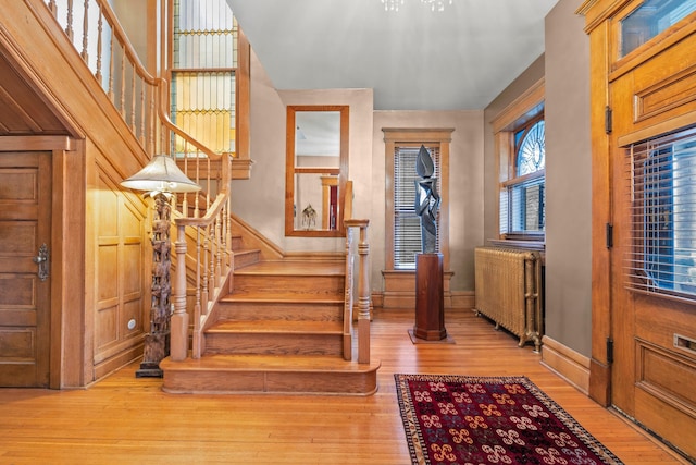 foyer with radiator, light hardwood / wood-style floors, and a notable chandelier