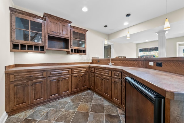 kitchen featuring sink, hanging light fixtures, black dishwasher, kitchen peninsula, and decorative columns