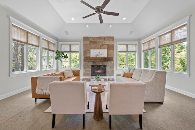 carpeted living room featuring a stone fireplace, ceiling fan, and a healthy amount of sunlight