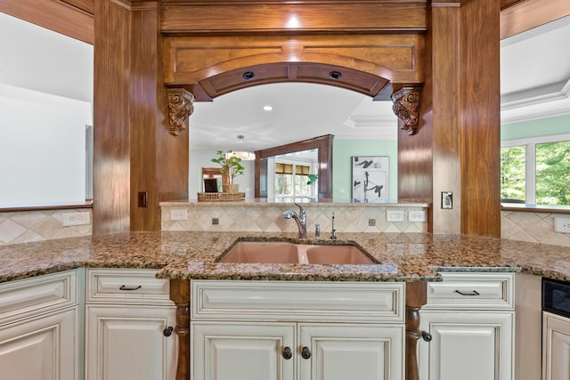 kitchen with backsplash, stone countertops, white cabinets, and sink