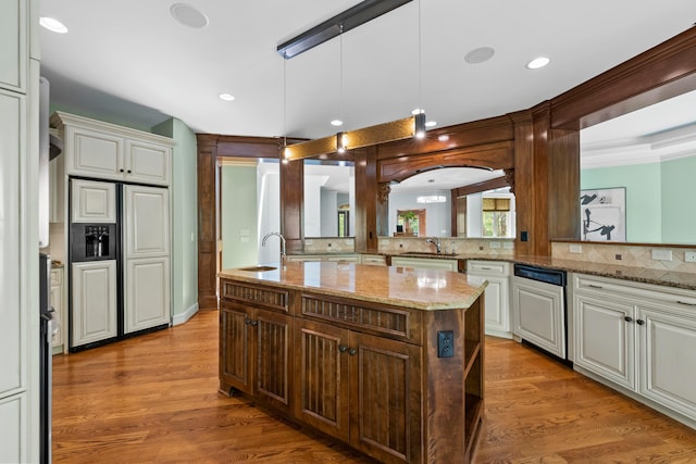 kitchen featuring backsplash, sink, hardwood / wood-style floors, hanging light fixtures, and an island with sink