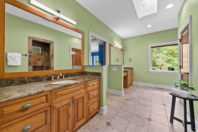 bathroom with tile patterned flooring, vanity, a skylight, and walk in shower