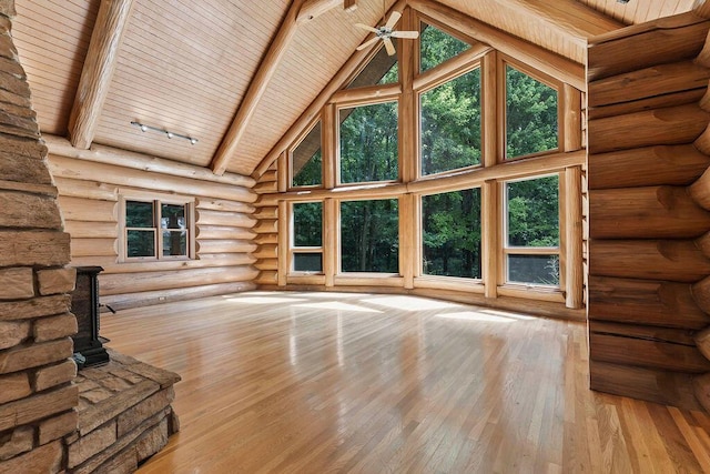 unfurnished living room featuring a wood stove, high vaulted ceiling, beam ceiling, light hardwood / wood-style floors, and wood ceiling