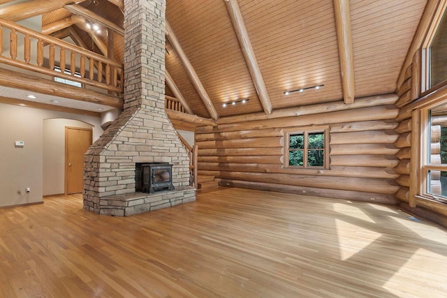 unfurnished living room featuring wood ceiling, light hardwood / wood-style floors, a wood stove, and high vaulted ceiling