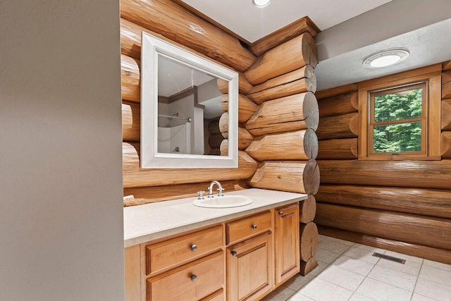 bathroom featuring tile patterned flooring, vanity, a shower, and rustic walls