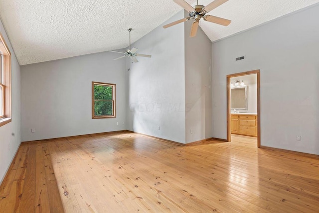 spare room with ceiling fan, a textured ceiling, high vaulted ceiling, and light hardwood / wood-style flooring