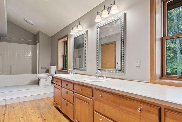 full bathroom featuring hardwood / wood-style floors, vanity, vaulted ceiling, toilet, and shower / bath combination