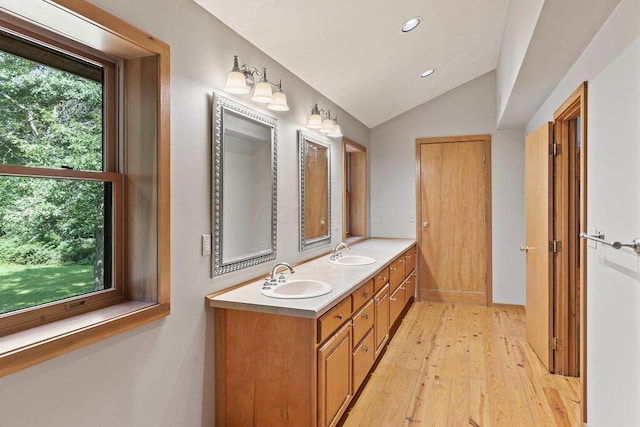 bathroom featuring wood-type flooring, vanity, and lofted ceiling