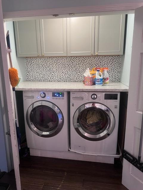 washroom featuring cabinets, dark hardwood / wood-style flooring, and washing machine and clothes dryer