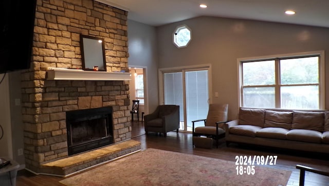 living room with dark hardwood / wood-style flooring, lofted ceiling, a wealth of natural light, and a brick fireplace