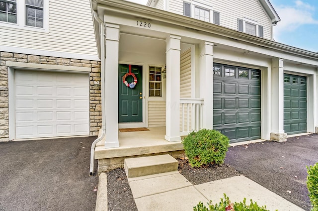 doorway to property with covered porch and a garage