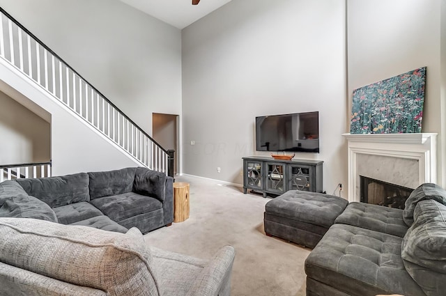 living room with a high end fireplace, light carpet, and high vaulted ceiling