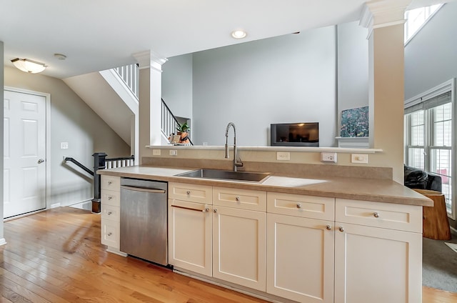 kitchen featuring kitchen peninsula, light wood-type flooring, stainless steel dishwasher, and sink