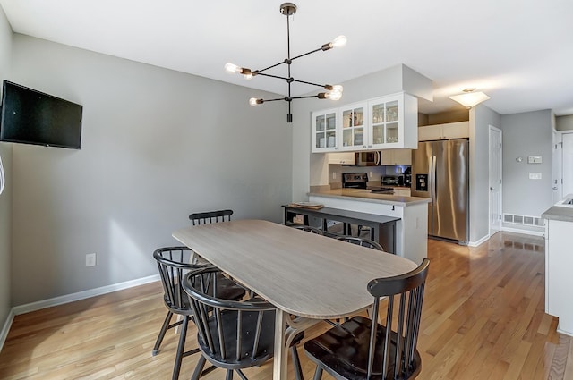 dining room with light hardwood / wood-style flooring and a notable chandelier