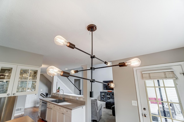 kitchen featuring dark wood-type flooring, white cabinetry, stainless steel dishwasher, and sink