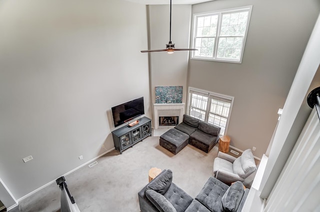 carpeted living room with ceiling fan and a towering ceiling