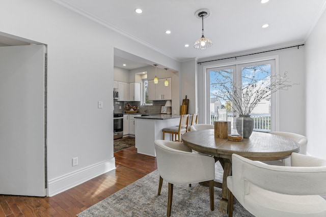 dining space with dark wood-type flooring, crown molding, and sink