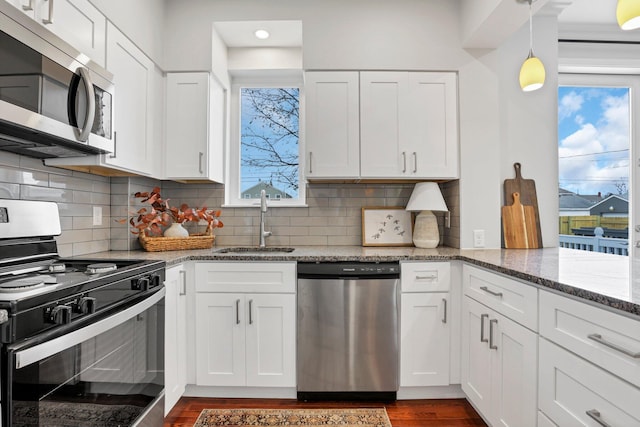 kitchen with stone counters, appliances with stainless steel finishes, sink, and white cabinets