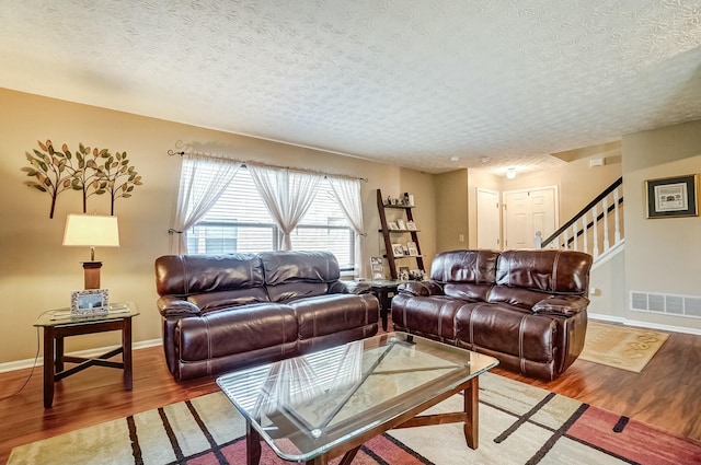 living area featuring stairway, wood finished floors, visible vents, and baseboards