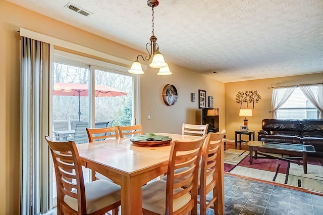 dining room featuring visible vents, a textured ceiling, and baseboards