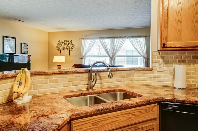 kitchen featuring black dishwasher, backsplash, a sink, a textured ceiling, and light stone countertops