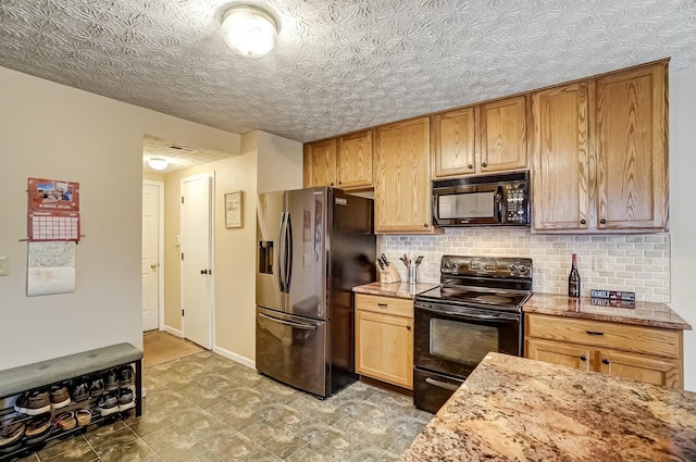 kitchen featuring decorative backsplash, black appliances, a textured ceiling, light stone countertops, and baseboards