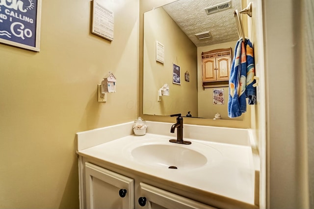 bathroom featuring a textured ceiling, vanity, and visible vents