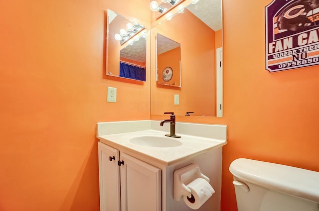 bathroom with toilet, a textured ceiling, and vanity